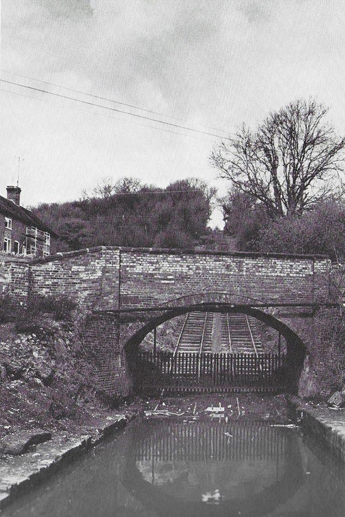 The brick bridge over the incline, seen across the still water of the basin in this photograph from the preservation era — one of the site's classic viewpoints, framed the same way then as it often is now. The reflection in the water hints at how much care went into refilling this basin after decades dry.
