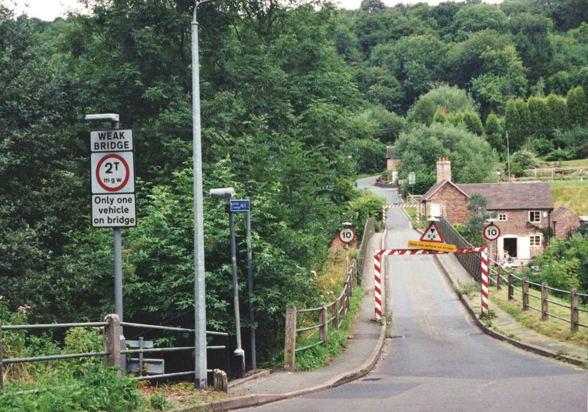 The signed approach today reads “only one vehicle on bridge”, backed up by height and width barriers across the road. Where a toll keeper once controlled traffic by hand and by conversation, these barriers now do the same job automatically, a quiet but telling shift in how the crossing is managed.