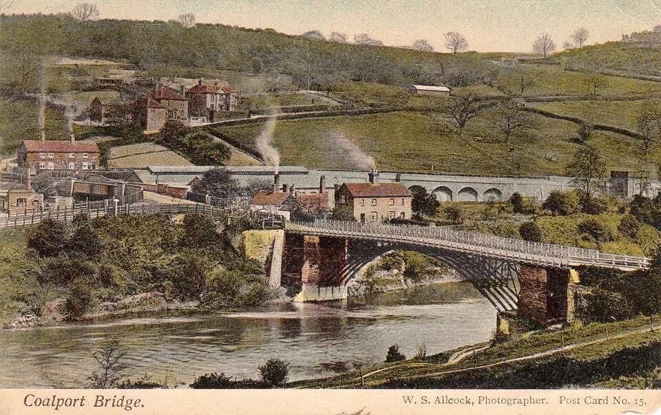 This hand-tinted postcard, W. S. Allcock's Post Card No. 15 from the early 1900s, gives the classic view of Coalport Bridge from the Shropshire bank. Look closely at the single cast-iron arch and the toll house at its northern end — the colourist's guesswork with the brickwork tones is part of what makes these cards such charming, if not always accurate, historical documents.