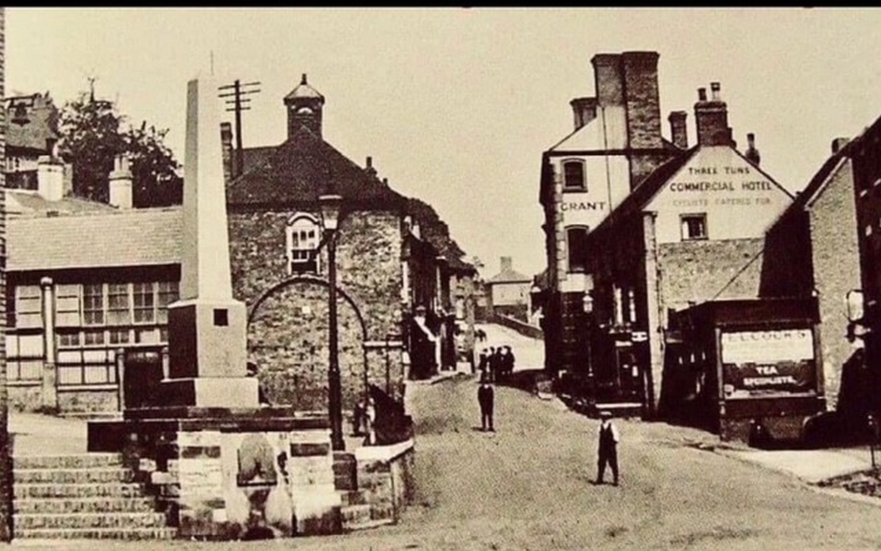 Looking up from the foot of the Market Place towards the Commercial Hotel, with the fountain commanding the entrance to the Square. Before traffic took over, this was the town's principal meeting place — you came here to trade, to drink and to hear what had happened. Exact date unknown.